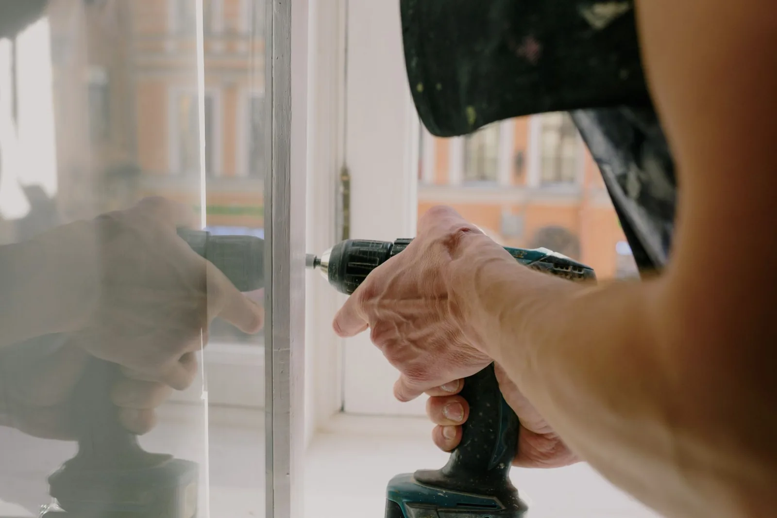 A workman installing a new white vinyl replacement window in a home